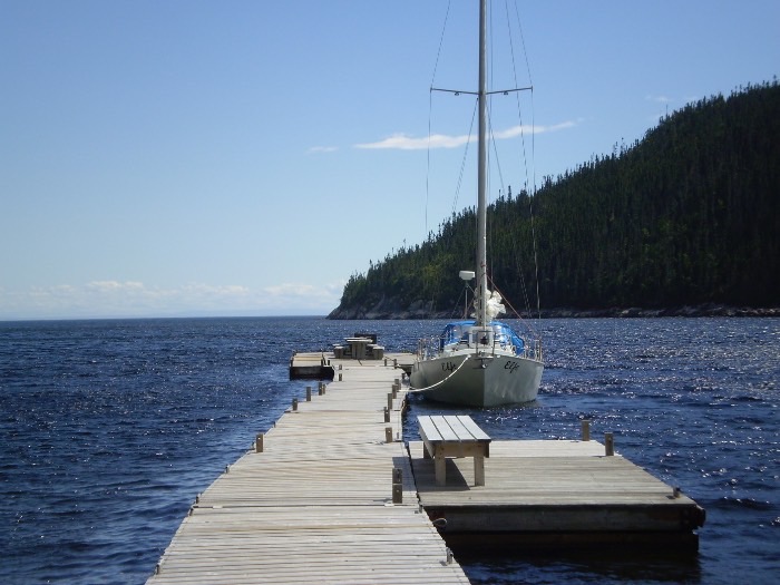 Elfe amarré au bout d'un long quai de bois, falaises boisées du Saguenay.