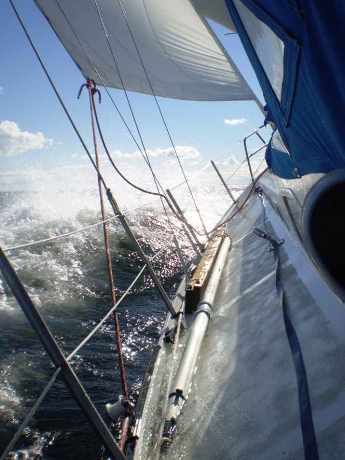 Elfe en navigation, gîté, embruns sur le pont, voiles établies.